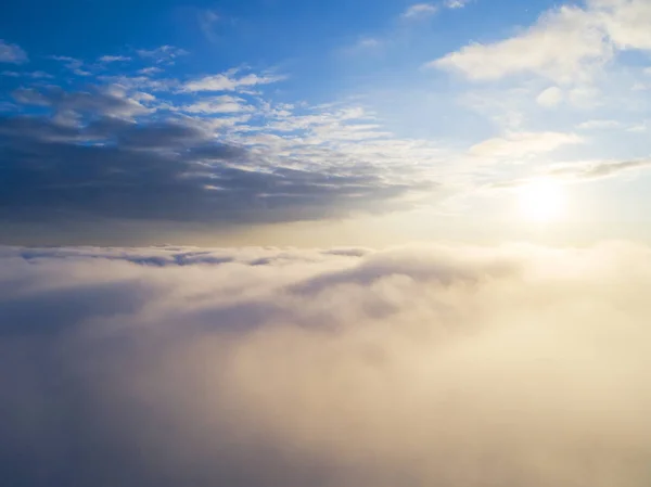 Aerial view White clouds in blue sky. Top view. View from drone. Aerial bird\'s eye view. Aerial top view cloudscape. Texture of clouds. View from above. Sunrise or sunset over clouds