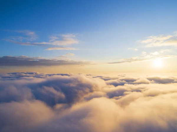Aerial view White clouds in blue sky. Top view. View from drone. Aerial bird\'s eye view. Aerial top view cloudscape. Texture of clouds. View from above. Sunrise or sunset over clouds