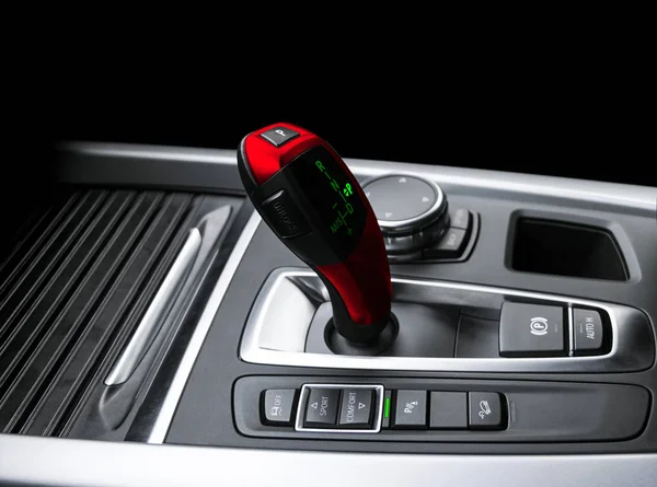 Red Automatic gear stick of a modern car. Modern car interior details. Close up view. Car detailing. Automatic transmission lever shift isolated on black background. Black leather interior with stitching.