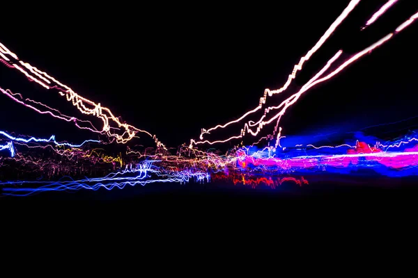 Cars light trails on a curved highway at night. Night traffic trails. Motion blur. Night city road with traffic headlight motion. Cityscape. Light up road by vehicle motion blur. Abstract view Cars on motion with long exposure