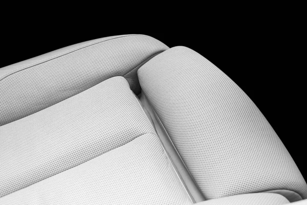White leather interior of the luxury modern car. Perforated white leather comfortable seats with stitching isolated on black background. Modern car interior details. Car detailing. Car inside