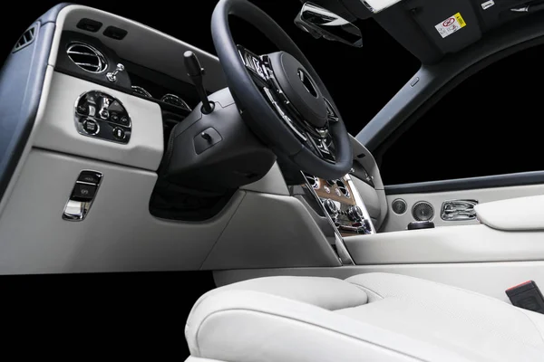 Modern luxury car white leather interior with natural wood panel. Part of leather car seat details with stitching. Interior of prestige modern car. White perforated leather. Car detailing. Car inside