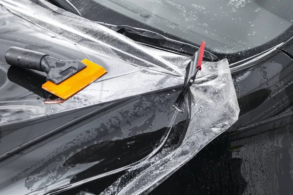 Especialista en envoltura de automóviles poniendo papel de vinilo o película en el coche. Película protectora en el coche. Aplicar una película protectora al coche con herramientas. Detallando el coche. Película transparente. Protección de pintura para coche. Recorte —  Fotos de Stock