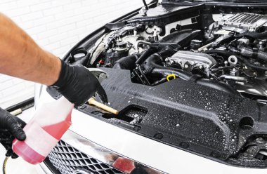 Şampuan ve fırça ile araba motor Temizleme bir adam. Araba ayrıntılı veya kavram valeting. Seçici odak. Araba ayrıntılı. Süngerle Temizleme. Temizlik işçisi. Oto yıkama kavramı çözüm temizlemek için
