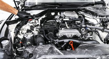 Şampuan ve fırça ile araba motor Temizleme bir adam. Araba ayrıntılı veya kavram valeting. Seçici odak. Araba ayrıntılı. Süngerle Temizleme. Temizlik işçisi. Oto yıkama kavramı çözüm temizlemek için