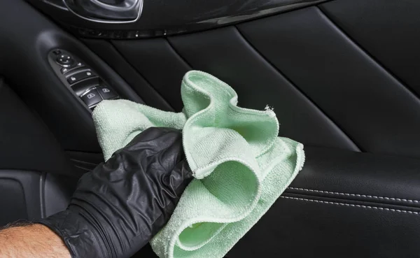 A man cleaning car seat with blue microfiber cloth. Car detailing or valeting concept. Selective focus. Car detailing. Cleaning with sponge. Worker cleaning. Car wash concept solution to clean