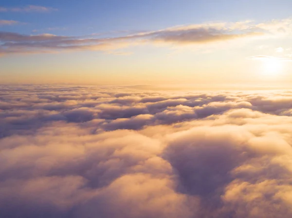 Aerial view White clouds in blue sky. Top view. View from drone. Aerial bird\'s eye view. Aerial top view cloudscape. Texture of clouds. View from above. Sunrise or sunset over clouds