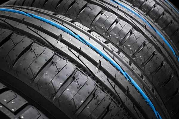 Studio shot of a set of summer car tires on black background. Tire stack background. Car tyre protector close up. Black rubber tire. Brand new car tires. Close up black tyre profile. Car tires in a row — Stock Photo, Image