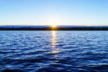 Su yüzeyi. Sunset gökyüzü arkaplanının görüntüsü. Deniz üzerinde akşam gökyüzü bulutları ile dramatik altın gün batımı gökyüzü. Kristal berrak deniz suyu dokusunun görüntüsü. Manzara. Küçük dalgalar. Su yansıması