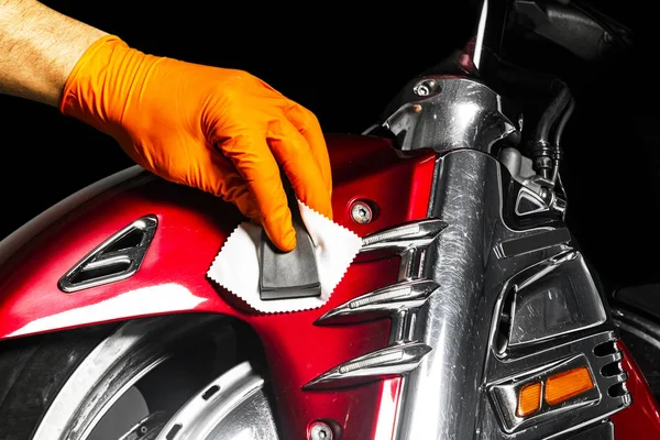 Car polish wax worker hands applying protective tape before polishing. Buffing and polishing motorcycle. Car detailing. Man holds a polisher in the hand and polishes the motorcycle