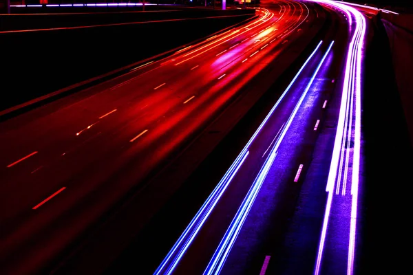 Les voitures éclairent les sentiers sur une route courbe la nuit. Trafic nocturne. Flou de mouvement. Route de nuit avec feux de circulation. Paysage urbain. Éclairage route par véhicule flou de mouvement . — Photo