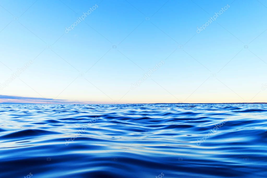 Water surface. View of a Sunset sky background. Dramatic gold sunset sky with evening sky clouds over the sea. View of a Crystal clear sea water texture. Landscape. Small waves. Water reflection