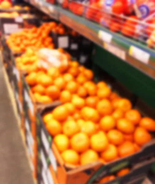 Blurred fresh fruits and vegetables at retail store. Abstract background of supermarket. Grocery market blurred background. Fruits in store racks. Interior shopping mall defocused background