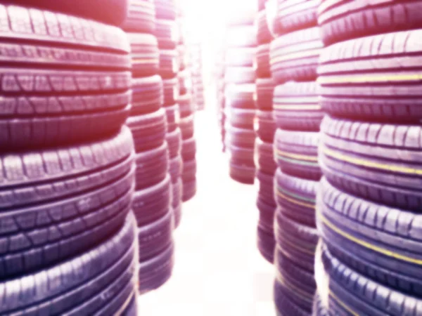 Fond flou abstrait avec des pneus de voiture à vendre. Flou photo de beaucoup de pneus de voiture dans le magasin à vendre. Pièces de voiture magasin fond bokeh. Éclairage doux . — Photo