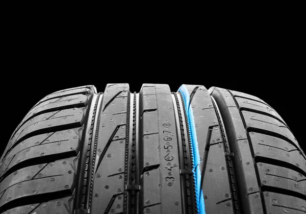 Studio shot of a set of summer car tires on black background. Tire stack background. Car tyre protector close up. Black rubber tire. Brand new car tires. Close up black tyre profile. Car tires in a row