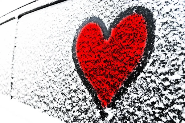 Symbol czerwonego serca na zamarzniętym oknie samochodu. Kształt serca narysowany na śniegu na przedniej szyby samochodu. Serce śnieg. Dekoracje świąteczne i akcesoria — Zdjęcie stockowe