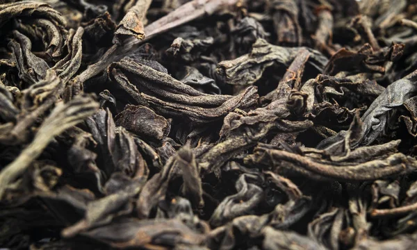 Macro shot of a high quality black tea. Black tea background close up. Leaf closeup. Background of dried tea leaves of dark color. Macro photo. Pile of black tea leaves. — Stock Photo, Image