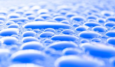 Şeffaf durgun su açık mavi arka plan üzerinde düşer. Mavi su damlaları. Camın üzerine yağmur damlaları. Mavi soyut su damla arka plan. Su yüzeyi