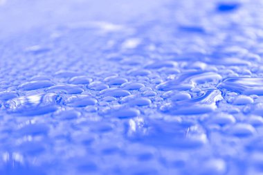 Şeffaf durgun su açık mavi arka plan üzerinde düşer. Mavi su damlaları. Camın üzerine yağmur damlaları. Mavi soyut su damla arka plan. Su yüzeyi