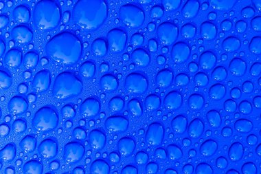 Şeffaf durgun su açık mavi arka plan üzerinde düşer. Mavi su damlaları. Camın üzerine yağmur damlaları. Mavi soyut su damla arka plan. Su yüzeyi