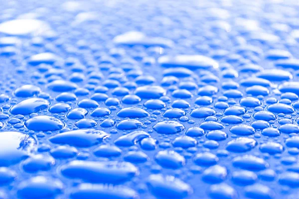Διαφανές ακόμα νερό σταγόνες σε ανοιχτό μπλε φόντο. Μπλε σταγόνες νερού. Σταγόνες βροχής στο γυαλί. Μπλε αφηρημένο φόντο νερό σταγόνα. Επιφάνεια νερού — Φωτογραφία Αρχείου