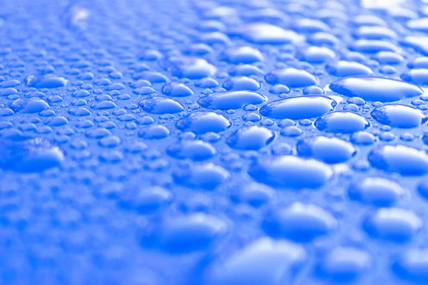 透明な静水は、水色の背景にドロップします。青い水が落ちるガラスに雨が降る青い抽象的な水滴の背景。水面 — ストック写真