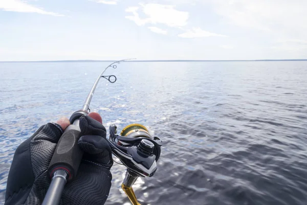 Fishing on the lake. Hands of fisherman with fishing rod. Macro shot. Fishing rod and hands of fisherman over lake water. Spinning rod. Fishing tackle — Stock Photo, Image