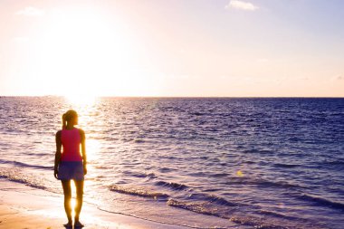 Kız siluet plaj gün batımı ayakta arıyorum. Okyanusu günbatımı. Tropikal plaj. Seyahat kavramı. Batımını kız. Model kız siluet günbatımı gökyüzü üzerinde. Yüzme ve yaz sahilde günbatımı üzerinde sıçramasına.