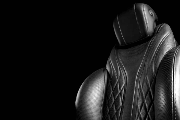 Черный кожаный интерьер роскошного современного автомобиля. Перфорированные кожаные удобные сиденья с прострочкой на черном фоне. Современные детали интерьера автомобиля. Детализирую машину. Черное и белое — стоковое фото