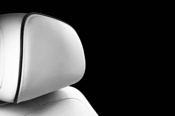 White leather interior of the luxury modern car. Perforated white leather comfortable seats with stitching isolated on black background. Modern car interior details. Car detailing. Car inside. Black and white
