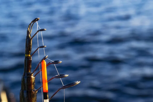 Rybářský prut s čárou a plovoucí blízko. Rybářská tyč v držáku tyčinky v rybářském člunu v den rybolovu. Kruhy na rybářské tyči. Rybářské náčiní. Vířící cívka. — Stock fotografie
