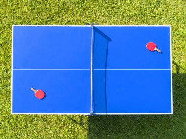 Havadan mavi masa tenisi veya masa tenisi. Yakın çekim pinpon ağı. Ping pong net ve çizgi kapatın. Üst görünüm iki masa tenisi veya ping pong raketleri veya kürekler ve net ile mavi bir masada top