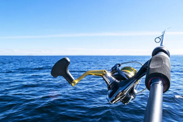 Vara de pesca girando com a linha de close-up. Haste de pesca em suporte de haste no barco de pesca devido ao dia da pesca. Anéis de cana de pesca. Equipamento de pesca. Carretel de fiação de pesca . — Fotografia de Stock