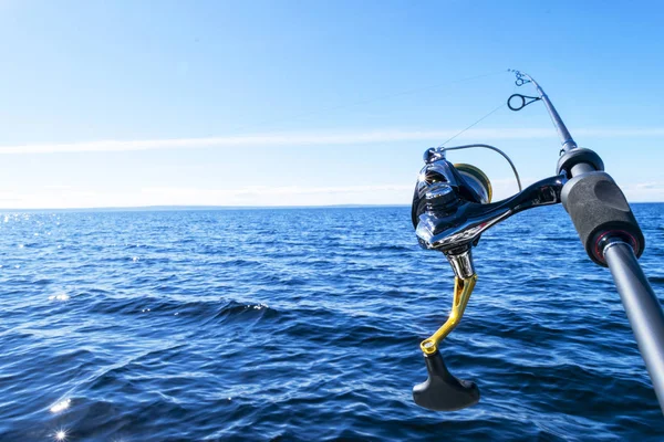 Vara de pesca girando com a linha de close-up. Haste de pesca em suporte de haste no barco de pesca devido ao dia da pesca. Anéis de cana de pesca. Equipamento de pesca. Carretel de fiação de pesca . — Fotografia de Stock