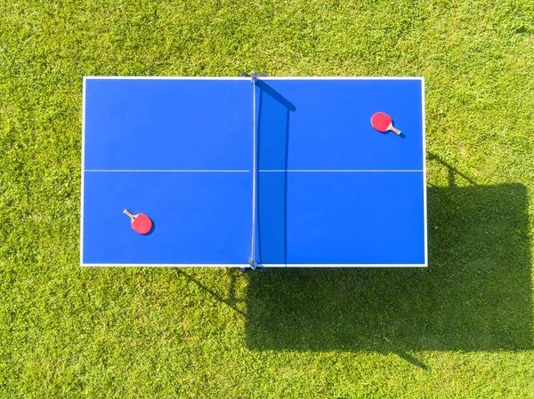 Vista aérea azul tênis de mesa ou pingue-pongue. Fechar a rede de ping-pong. Feche a rede de pingue-pongue e linha. Vista superior duas raquetes de tênis de mesa ou ping pong ou remos e bola em uma mesa azul com rede — Fotografia de Stock