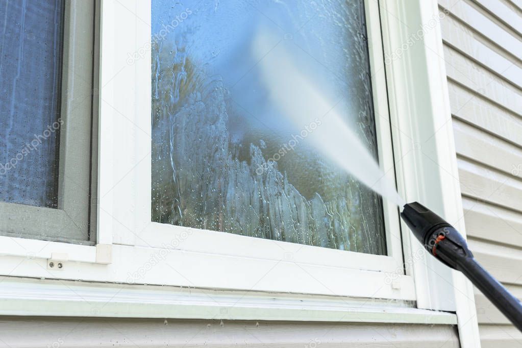 Cleaning service washing building facade and window with pressure water. Cleaning dirty wall with high pressure water jet. Power washing the wall. Cleaning the facade of the house. Before and after washing