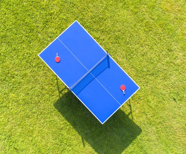 Vue aérienne tennis de table bleu ou ping-pong. Filet de ping-pong en gros plan. Fermez le filet et la ligne de ping-pong. Vue de dessus deux raquettes ou palettes de ping-pong ou de ping-pong et balle sur une table bleue avec filet — Photo