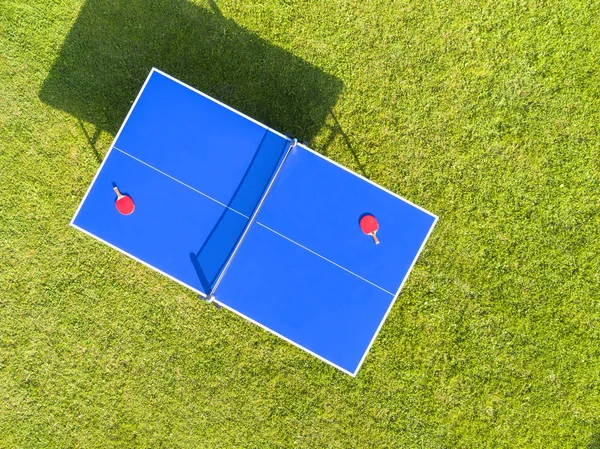 Aerial view blue table tennis or ping pong. Close-up ping-pong net. Close up ping pong net and line. Top view two table tennis or ping pong rackets or paddles  and ball on a blue table with net