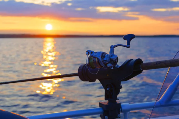 Fishing rod spinning with the line close-up. Fishing rod in rod holder in fishing boat due the fishery day at the sunset. Fishing rod rings. Fishing tackle. Fishing spinning reel. — Stock Photo, Image