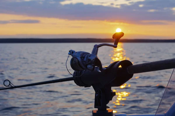 Fishing rod spinning with the line close-up. Fishing rod in rod holder in fishing boat due the fishery day at the sunset. Fishing rod rings. Fishing tackle. Fishing spinning reel. — Stock Photo, Image