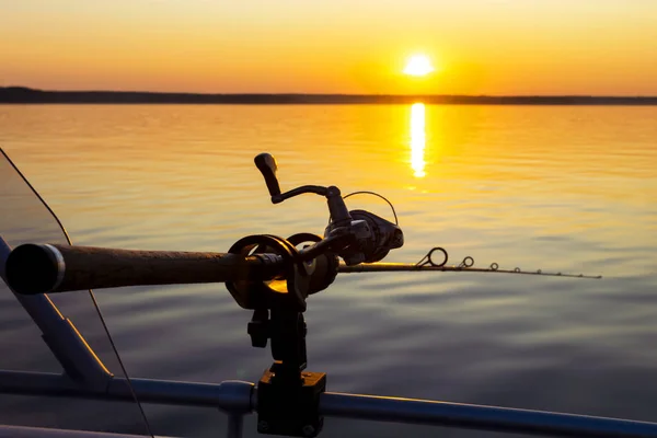 Fiskespöet snurrar med linan närbild. Fiskespö i spöhållare i fiskebåt på grund av fiskedagen vid solnedgången. Fiskespökringar. Fiskeutrustning. Rulle för fiske. — Stockfoto