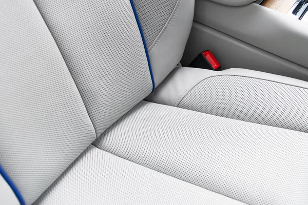 White leather interior of the luxury modern car. Perforated white leather comfortable seats with stitching isolated on black background. Modern car interior details. Car detailing. Car inside