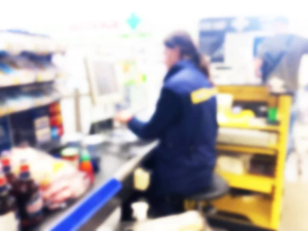 Размытый фон кассира с длинной линией людей у кассы супермаркета. Размытые клиенты платят наличными продавцам, полная тележка продуктов. Концепция кассового учета. Размытый магазин — стоковое фото