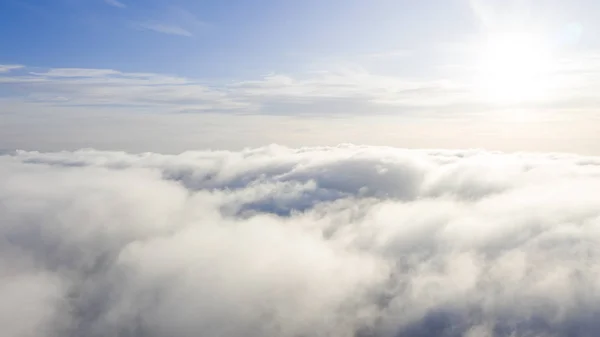 Aerial view White clouds in blue sky. Top view. View from drone. Aerial bird\'s eye view. Aerial top view cloudscape. Texture of clouds. View from above. Sunrise or sunset over clouds