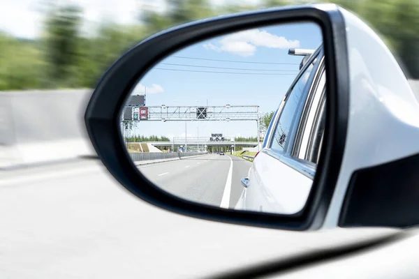 Car drive along a high road with motion blur background. Car side mirror with traffic. Car rear view mirror with reflection of the traffic