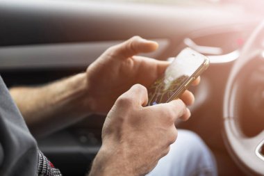 Arabada akıllı telefon kullanan bir erkek. Araba süren bir adam. Navigate ya da GPS için araba kullanımında akıllı telefon. Seyahat ederken cep telefonu sürücü elinde.