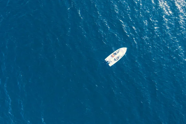 Aerial view fisherman on boat at the ocean. Top view beautiful seascape with the fishing boat. Aerial view fishing motor boat with angler. Ocean sea water wave reflections. Motor boat in the ocean.