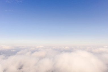 Mavi gökyüzünde hava manzaralı beyaz bulutlar. İnsansız hava aracı görüntüsü. Üst hava manzarası bulutlu. Bulutların dokusu. Yukarıdan bak. Bulutların üstünde gün doğumu ya da gün batımı. Panorama bulutları