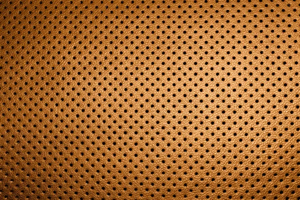 Modern luxury car brown leather interior. Part of perforated orange leather car seat details. Perforated leather texture background. Texture, artificial leather with stitching. Perforated leather seats