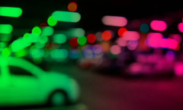 Blurred cars in car parking lot in shopping mall. Bokeh lights background. Abstract blur car parking lot for background. Blurred cars parking and bokeh ligh concept